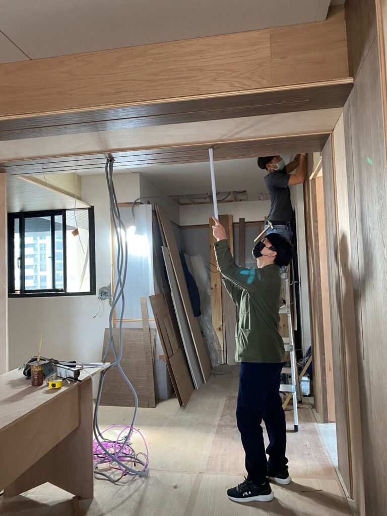 玄關大樑施工過程，木作包覆樑體、整理天花線條與牆面收邊